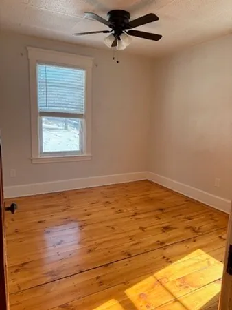 a view of a room with wooden floor and a ceiling fan