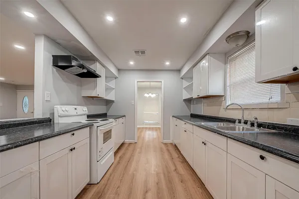 a large kitchen with stainless steel appliances granite countertop a lot of counter space and wooden floors