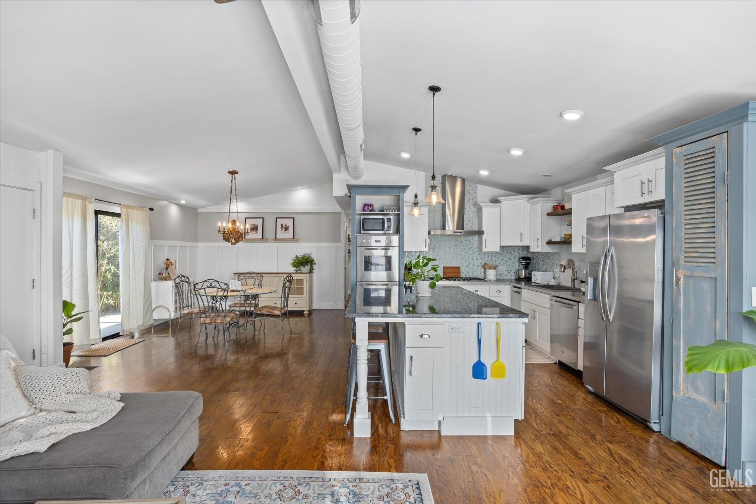 Undisclosed Address Bakersfield, CA 93306 - Photo 11 of 39 a kitchen with stainless steel appliances kitchen island granite countertop a refrigerator a stove top oven a sink dishwasher and white cabinets with wooden floor