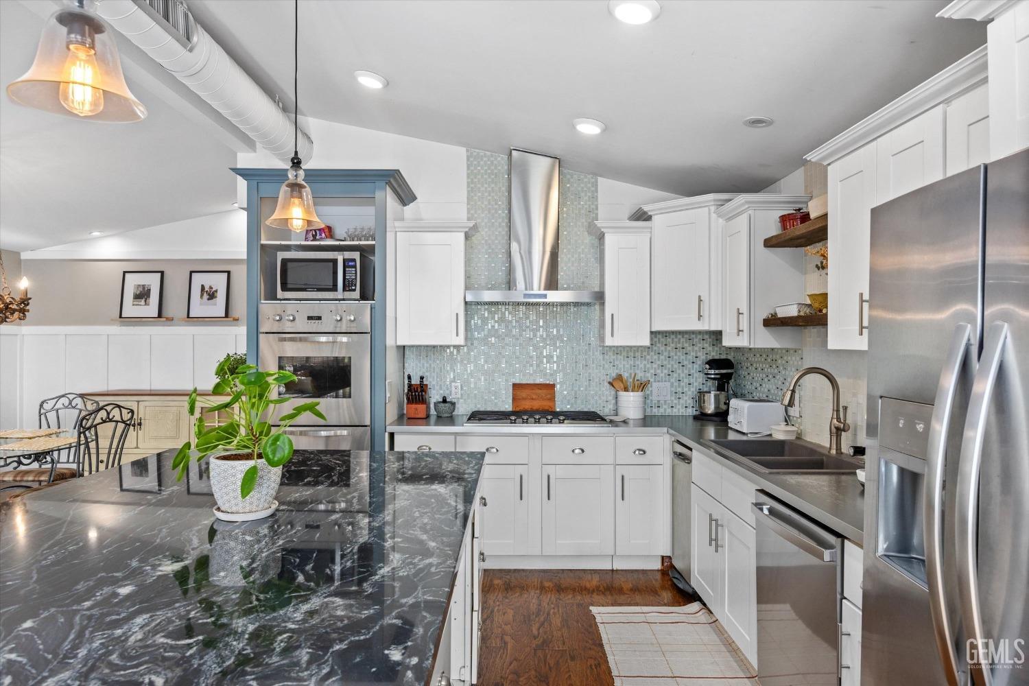 Undisclosed Address Bakersfield, CA 93306 - Photo 18 of 39 a kitchen with stainless steel appliances a sink a kitchen island a stove a refrigerator cabinets a dining table and chairs