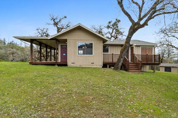 a view of a house with wooden deck and a yard