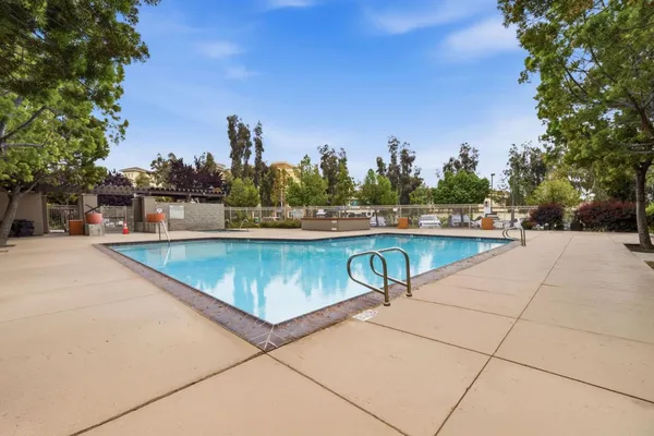 a view of swimming pool with outdoor seating and trees in the background
