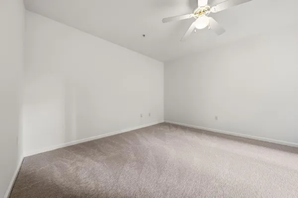 an empty room with windows and chandelier fan