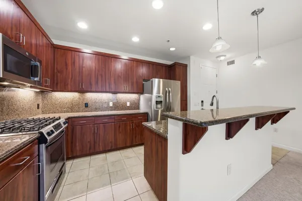 a kitchen with stainless steel appliances granite countertop a sink a stove and a refrigerator