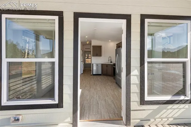 a view of a hallway with wooden floor and a living room