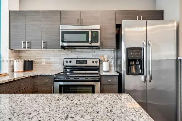 a kitchen with granite countertop a refrigerator and a stove top oven