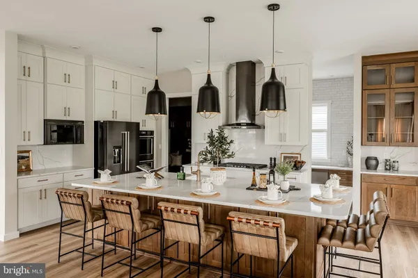 a kitchen with stainless steel appliances kitchen island granite countertop a dining table chairs and white cabinets