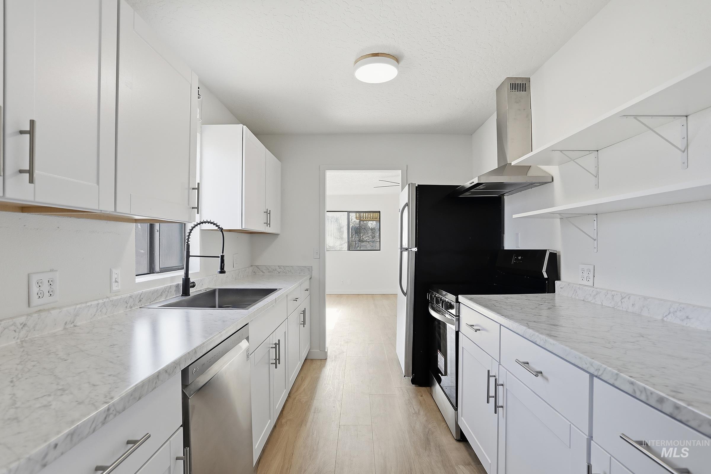 Kitchen featuring open shelves, stainless steel appliances, white cabinets, range hood, and light wood-style flooring