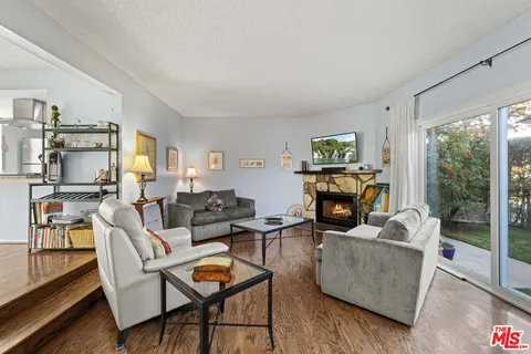a living room with furniture large window and wooden floor