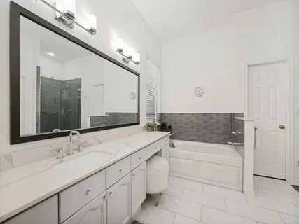 a bathroom with a sink double vanity granite tub and a mirror