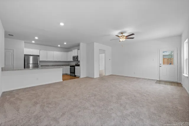 a view of a kitchen with a stove cabinets a ceiling fan and wooden floor
