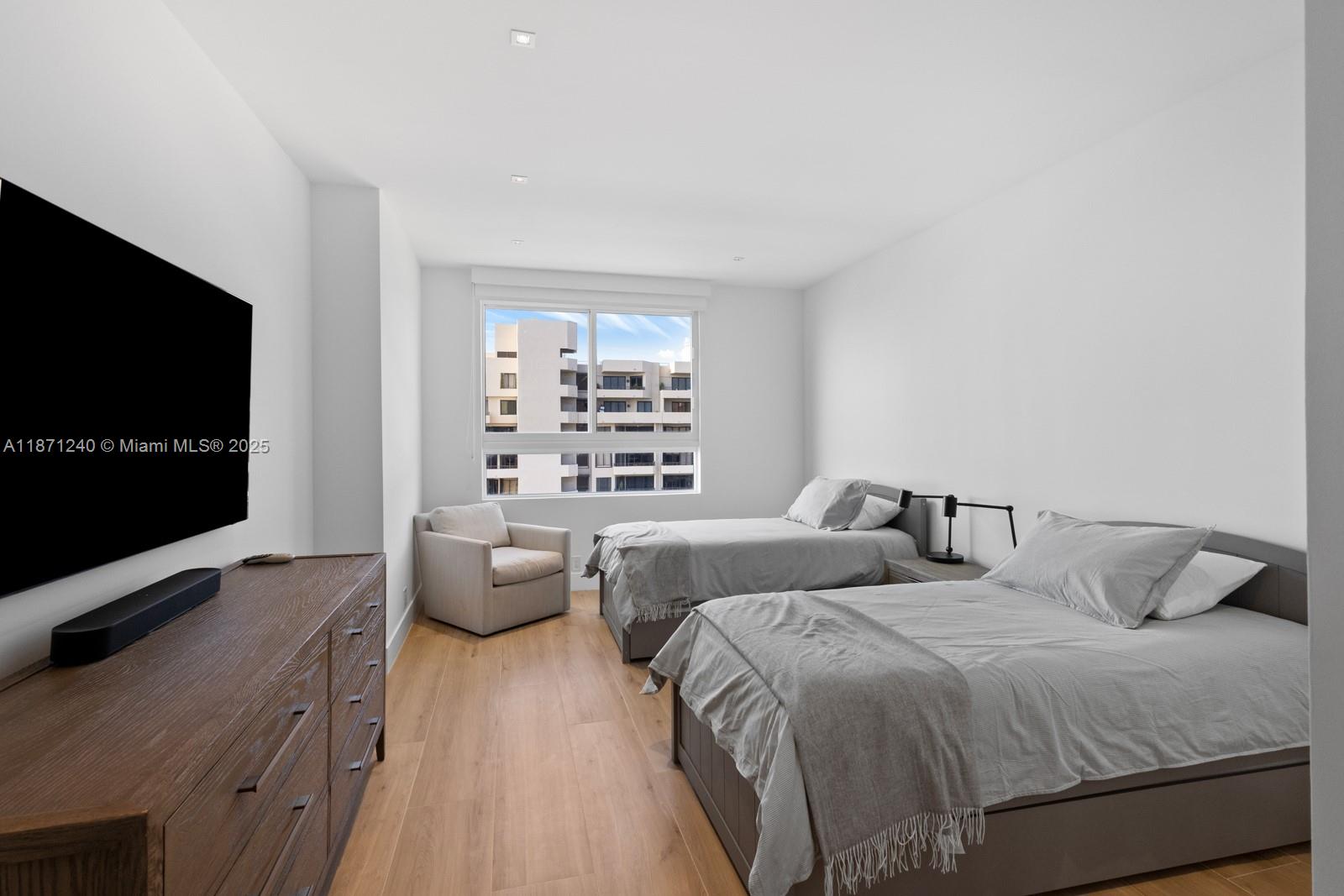 251 Crandon Boulevard, Unit 1036 Key Biscayne, FL 33149 - Photo 16 of 38 a bedroom with two beds and a flat screen tv