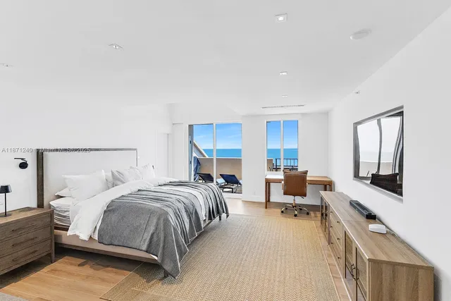 a bedroom with a bed couch table and two large window