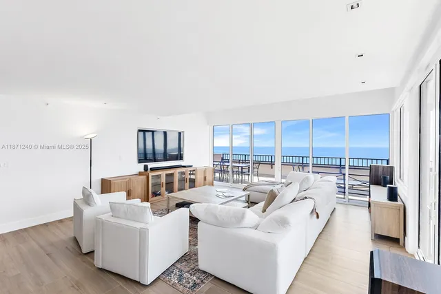 a living room with furniture large windows and wooden floor