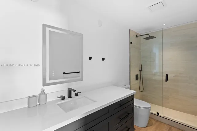 a bathroom with a granite countertop sink a toilet a shower and a mirror