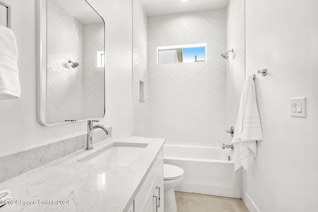 a bathroom with a granite countertop sink a toilet and shower