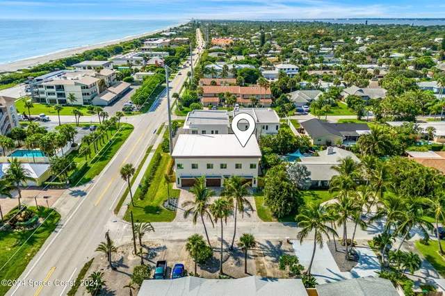 an aerial view of a city with lots of residential buildings ocean and mountain view in back