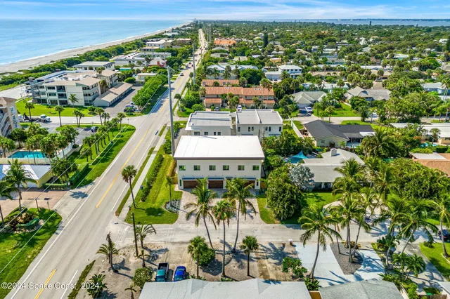 an aerial view of a city with lots of residential buildings ocean and mountain view in back