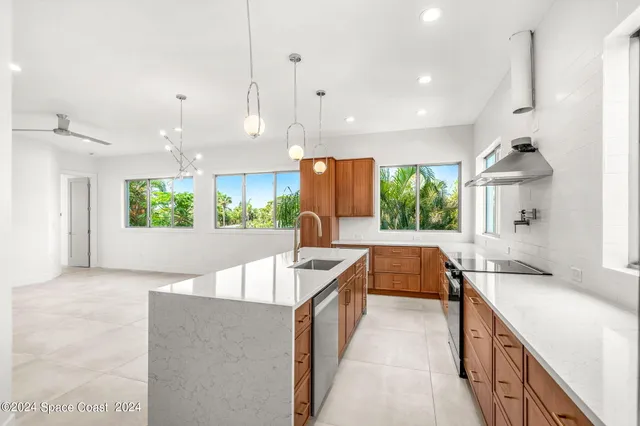 a kitchen with kitchen island a large counter top space a sink stainless steel appliances and windows