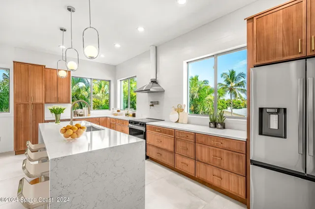 a large kitchen with kitchen island granite countertop a refrigerator a stove a sink dishwasher and a dining table with wooden floor