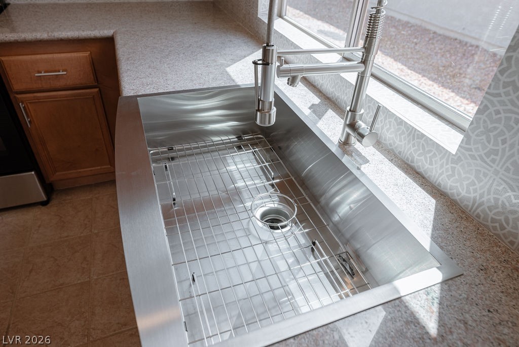 3591 Driving Range Street Las Vegas, NV 89122 - Photo 39 of 79 This kitchen showcases a durable stainless steel sink with modern faucet, set against a practical tiled floor.