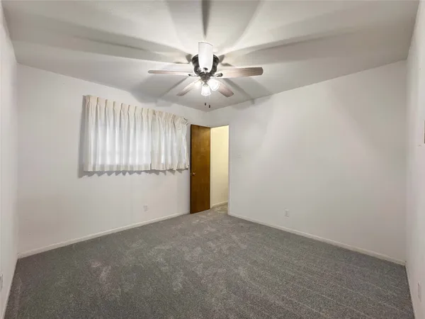 an empty room with chandelier fan and windows