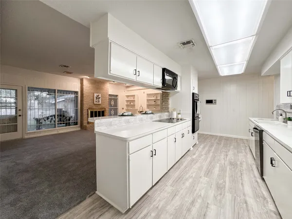 a large kitchen with stainless steel appliances granite countertop a lot of counter space and wooden floors