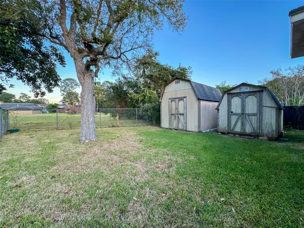 a view of a backyard with large trees and a small barn