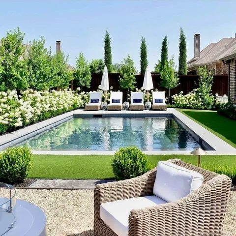 a view of swimming pool with outdoor seating and trees in the background