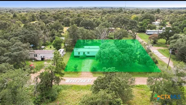 an aerial view of residential houses with outdoor space and trees