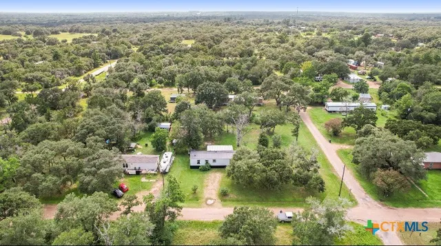 an aerial view of residential houses with outdoor space and trees