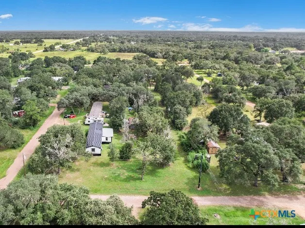 an aerial view of residential houses with outdoor space and trees