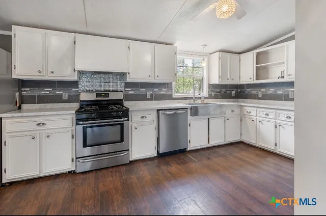 a kitchen with white cabinets stainless steel appliances and wooden floor