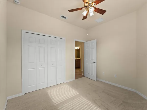 a view of an empty room and chandelier fan
