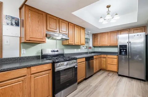 a kitchen with granite countertop stainless steel appliances and wooden cabinets