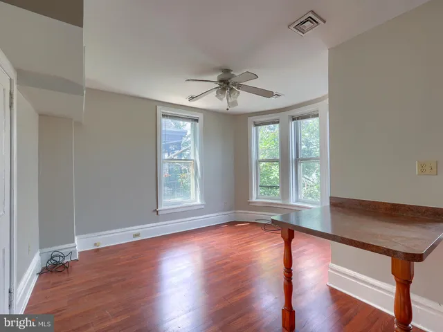 a kitchen with stainless steel appliances granite countertop a stove top oven a refrigerator a dining table and chairs with wooden floor