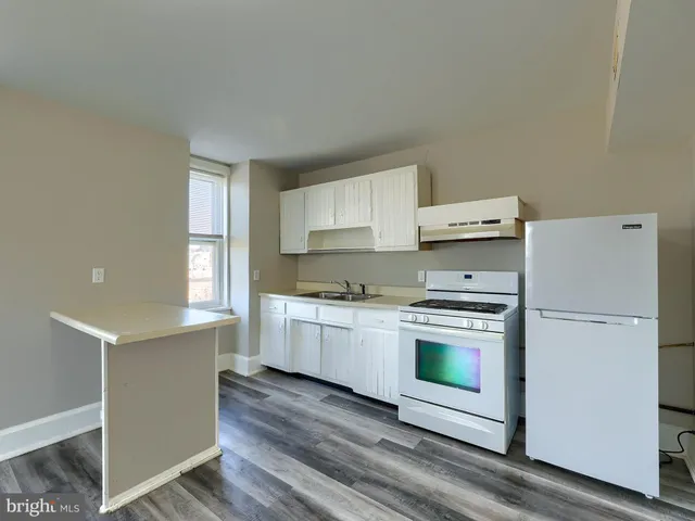 a kitchen with a refrigerator stove and wooden floor