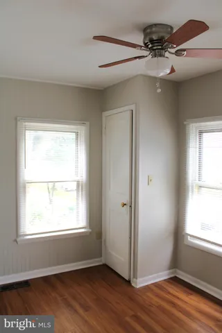 a view of an empty room with a window and wooden floor