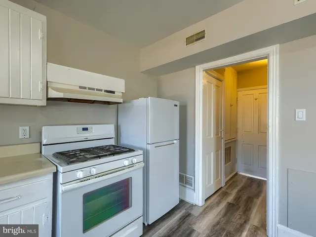 a kitchen with wooden floors and white appliances