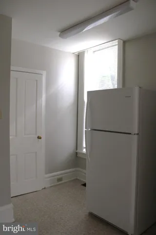 a view of a refrigerator in kitchen and a window