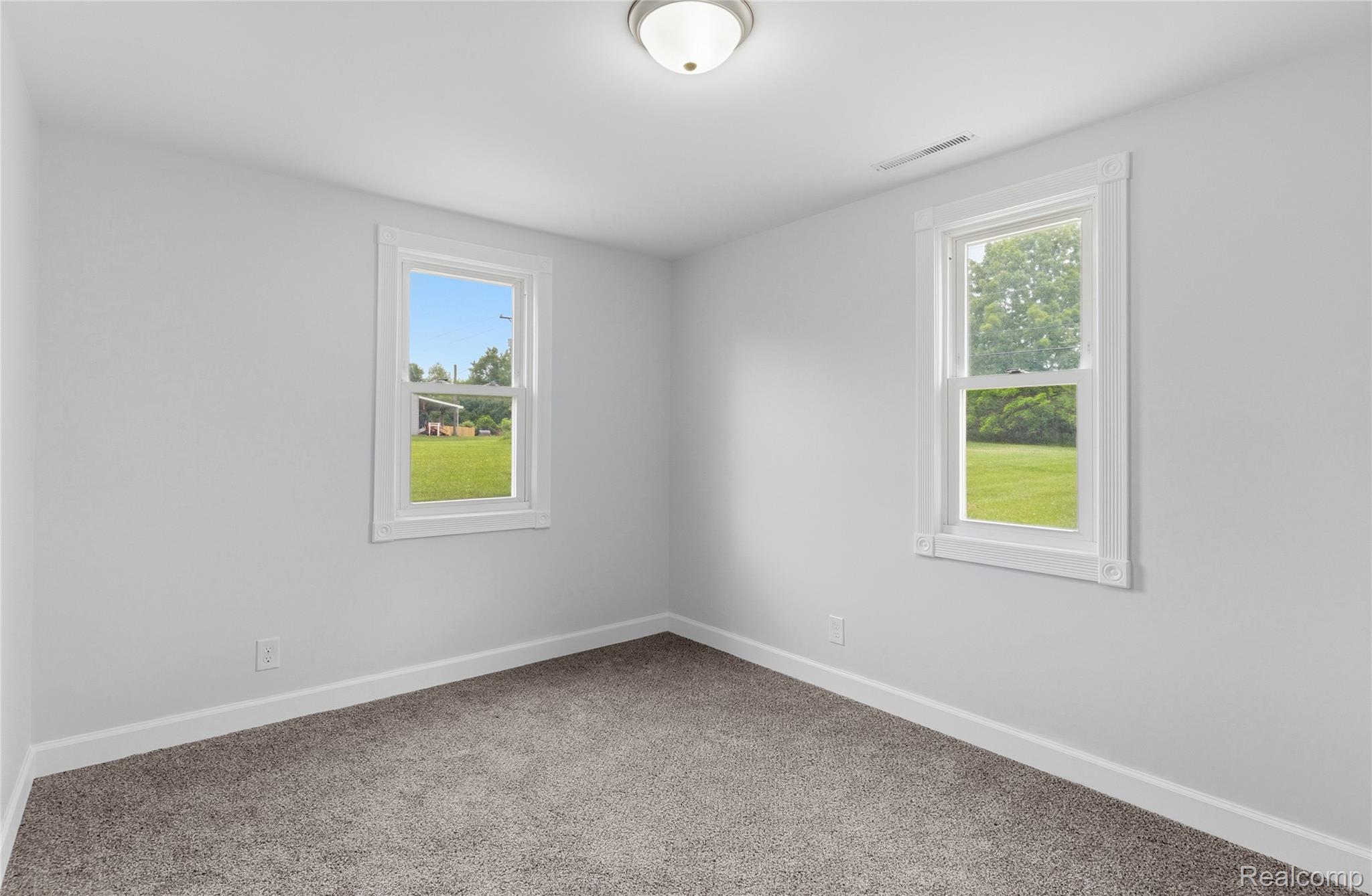 3241 East Frances Road Clio, MI 48420 - Photo 15 of 32 Bright interior room featuring two windows, neutral wall tones, and gray carpeting