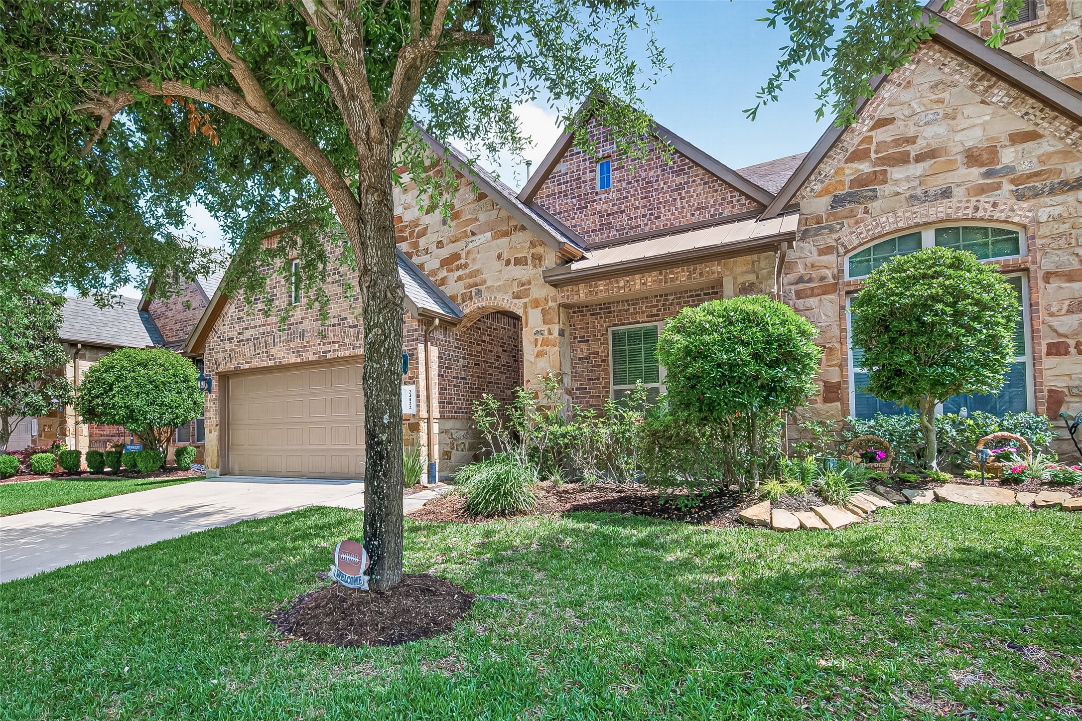 24122 Valencia Ridge Lane Katy, TX 77494 - Photo 2 of 46 Beautiful front exterior showcasing mature landscaping, stone accents, and a welcoming covered entry in the sought-after Towns at Seville community.
