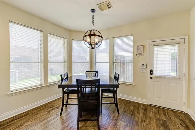 a dining room with wooden floor a chandelier a wooden table and chairs