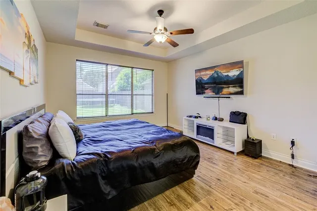 a bedroom with a bed a flat screen tv and a chandelier