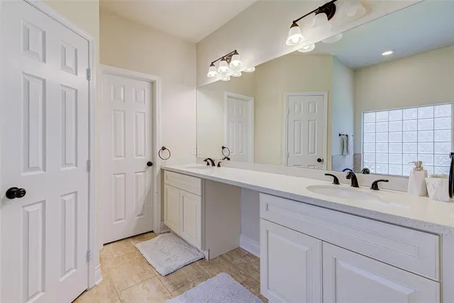 a bathroom with a double vanity sink a mirror and a bathtub