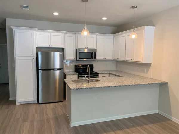 a kitchen with kitchen island a counter top space cabinets and stainless steel appliances