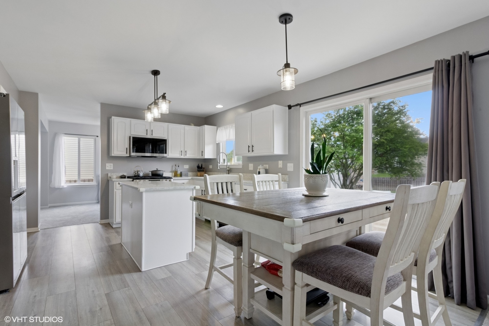 4300 Dobbins Street Plano, IL 60545 - Photo 10 of 31 a kitchen with stainless steel appliances kitchen island granite countertop a table chairs in it and wooden floors