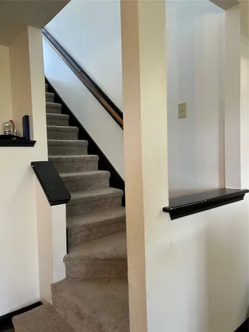 a view of staircase with white walls and railing