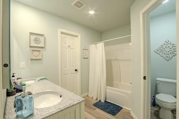 a bathroom with a granite countertop sink a toilet and shower
