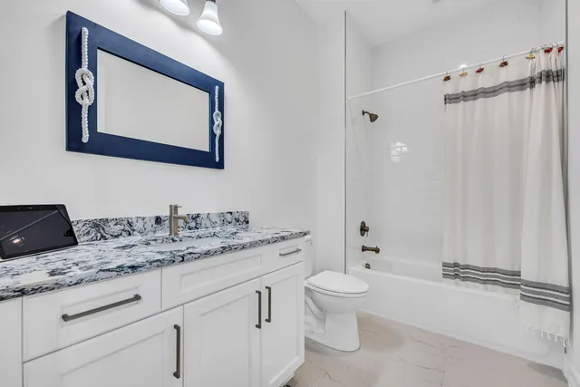 a bathroom with a granite countertop sink mirror vanity and toilet